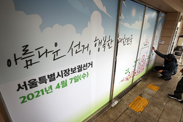 서울시장보궐선거를 80여 일 앞둔 18일 오후 종로구 서울특별시선거관리위원회 1층 출입구에서 관계자들이 '아름다운 선거 행복한 대한민국'슬로건 등을 래핑하고 있다. (사진=연합뉴스)