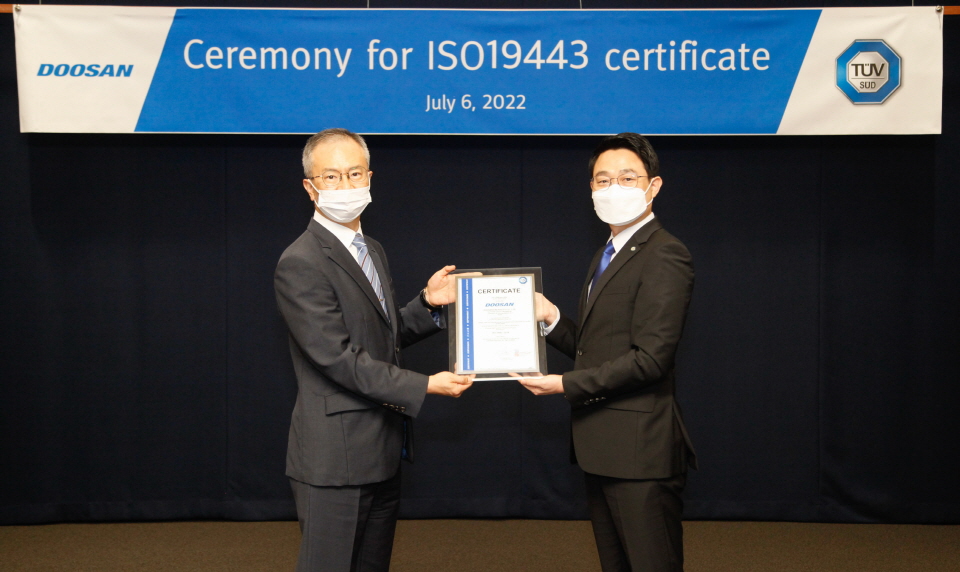 강홍규 두산에너빌리티 원자력BG 상무(왼쪽)와 서정욱 TUV SUD Korea 대표이사(오른쪽)가 지난달 분당두산타워에서 열린 ISO 19443 인증서 수여식에서 기념 촬영하는 모습. [사진=두산에너빌리티]